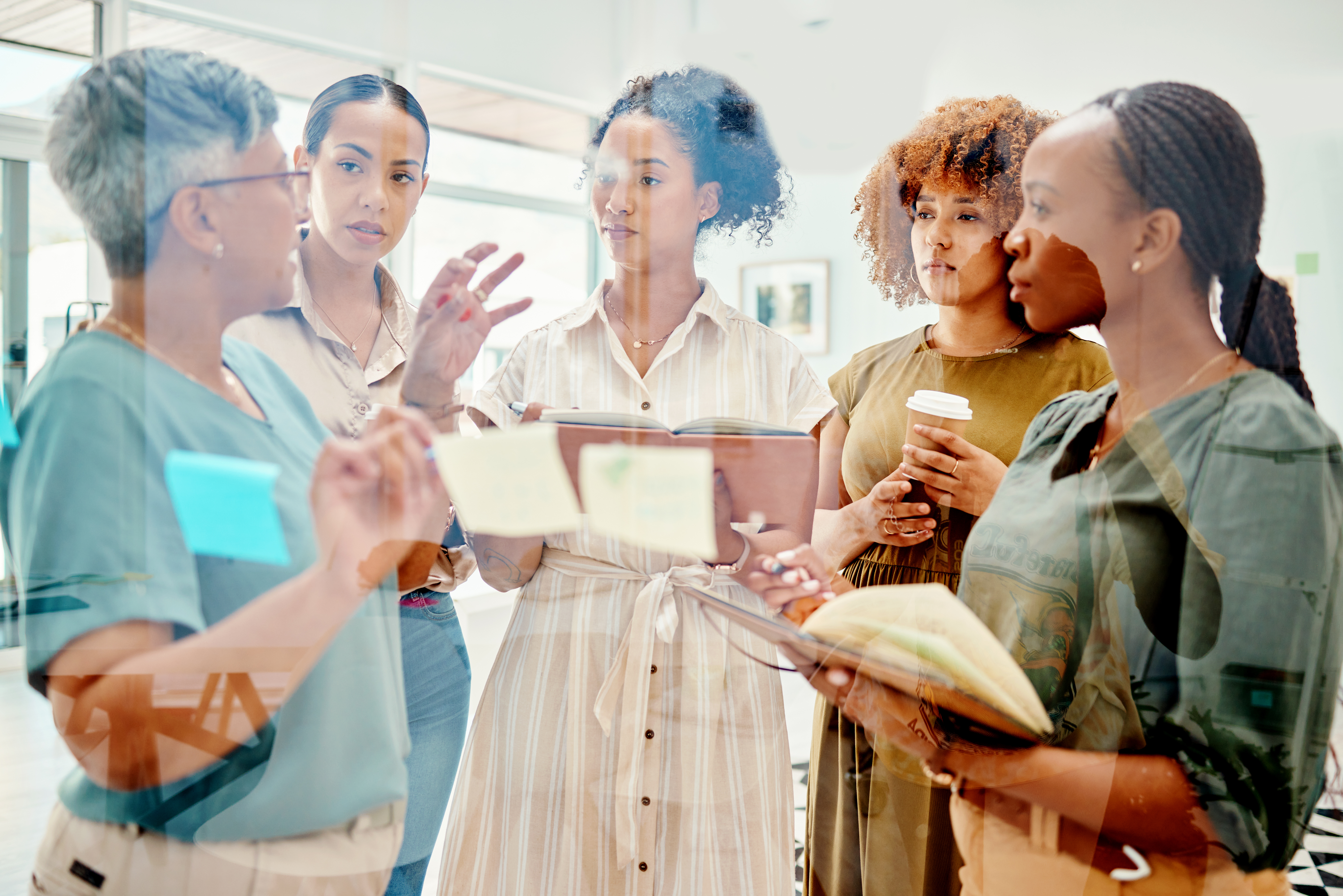 Creative women, meeting and planning schedule in team brainstorming, strategy or ideas at the office. Group of employees working together in startup project plan, discussion or tasks at the workplace